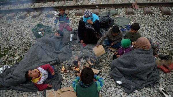 Refugees keep warm near a fire at a makeshift camp at the Greek-Macedonian border, near the Greek village of Idomeni on March 18, 2016, where thousands of refugees and migrants are stranded by the Balkan border blockade. (AFP/Daniel Mihailescu)