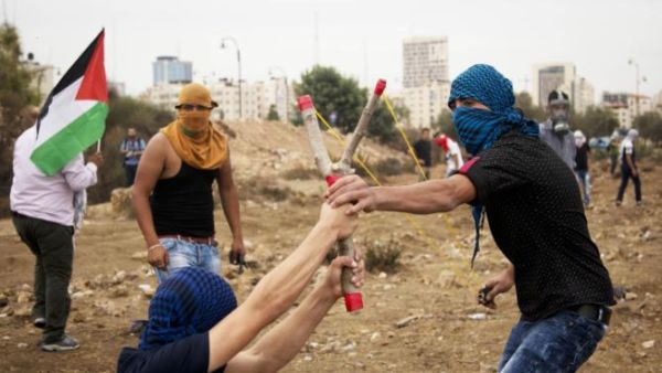 Palestinians prepare to launch a rock from a homemade slingshot during clashes with Israeli soldiers. (AFP/FIle)