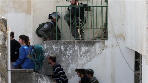 Israeli settlers under the escort of Israeli border police enter two homes in a building in Hebron. (AFP/File)