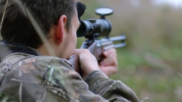 A man in camouflage and with guns in a forest belt on a spring hunt. (Shutterstock/ File Photo)