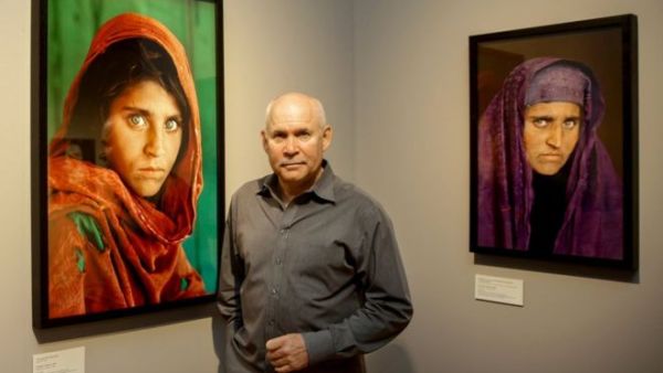 Photographer Steve McCurry poses next to his two portraits of Sharbat Gula, the 'Afghan Girl' from the famous National Geographic magazine cover in 1985. (AFP/File)