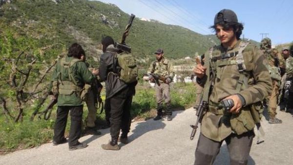 Rebel fighters gather along the road carrying their weapons near the village of Qasab and the border crossing with Turkey, in the northwestern province of Latakia, Syria, on March 23, 2014. (AFP/Amr Radwan Al-Homsi)