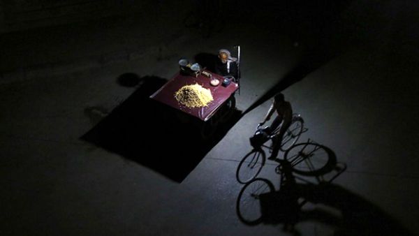 A Syrian man rides his bicycle past a man selling grains during a halt in fighting in Douma, in the Eastern Ghouta region, east of the capital Damascus. (AFP/File)
