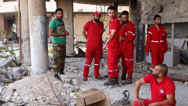 Members of the Red Crescent and a Syrian army soldier gather at the entrance of a damaged building in the government-controlled part of the besieged town of Daraya. (AFP/File)
