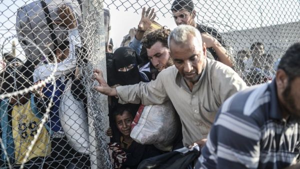 Syrians fleeing the war pass through border fences to enter Turkish territory illegally, near the Turkish border crossing at Akcakale in Sanliurfa province on June 14, 2015. (AFP/Bulent Kilic)