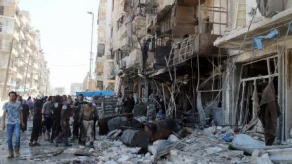سكان وأفراد من الدفاع المدني أمام مبنى مدمر عقب ضربة جوية في حلب يوم السبت
