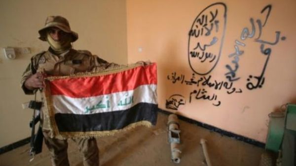 مقاتل عراقي موال للحكومة يحمل العلم الوطني داخل مقر لتنظيم الدولة خلال عملية تطهير حي الضباط في الفلوجة

