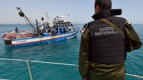 A member of the Tunisian Coast Guard observes a fishing boat. (AFP/File)