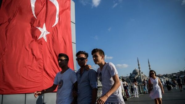 Young people walk on Galata bridge next to a giant Turkish national flag at Eminonu district in Istanbul on July 26, 2016. (Ozan Kose/ AFP)