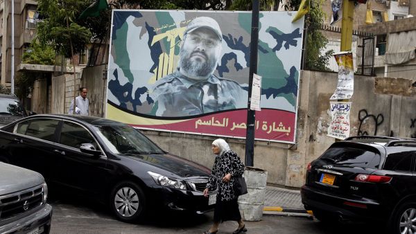 A woman walks beneath a poster of deceased Hezbollah senior member Imad Mughniyah in Beirut, Lebanon.  (AFP/Ramzi Haidar)