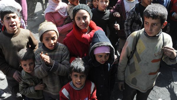 Palestinian children stand during a relief operation in Syria's besieged Yarmouk refugee camp, February 24, 2014. (AFP/SANA)