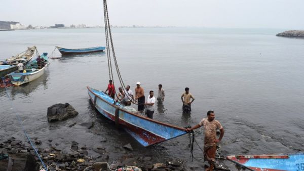 Yemeni men lift a damaged fishing boat out of the water following Cyclone Chapala on November 3, 2015, in the southern port city of Aden. (AFP/Saleh Al-Obeidi)