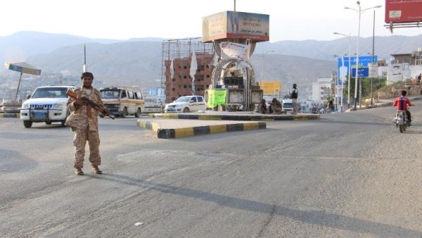 A picture taken on May 3, 2016 shows a Yemeni security forces member patrolling a street with a banner hung by Al-Qaeda militants in the Yemeni port of Mukalla, 300 miles east of Aden. (AFP/Stringer)