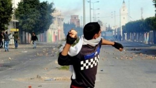 متظاهر يلقي حجرا خلال مواجهات مع الشرطة في منطقة رقويب قرب مدينة سيدي بوزيد