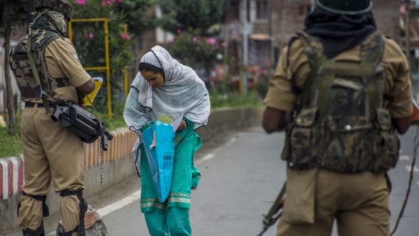 امرأة مسلمة تمر من بين جنديين هنديين في كشمير