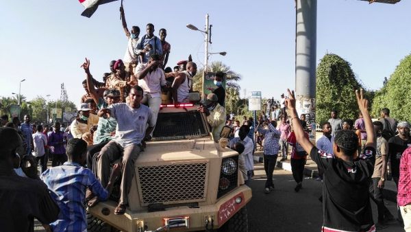 Sudanese protesters wave a national flag (AFP)