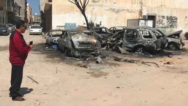 A Libyan man looks at damaged vehicles at the scene of an overnight rocket attack which no group claimed responsibility for so far in the Libyan capital Tripoli (AFP)
