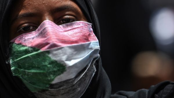 A masked Sudanese protester rallies outside the army complex in Sudan's capital Khartoum (AFP)