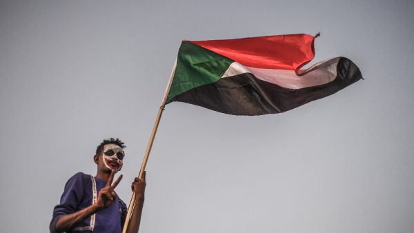 A Sudanese protestor waves a national flag during a protest  (AFP)