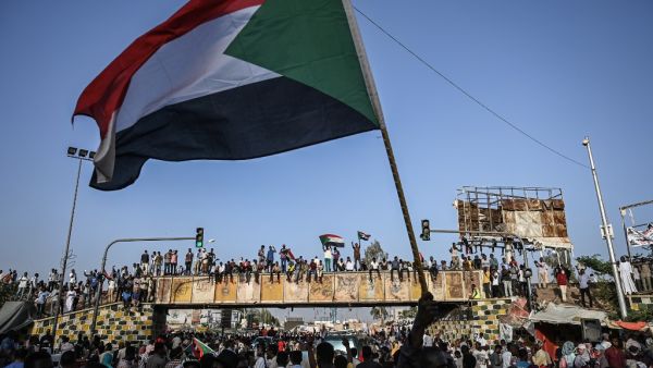 Sudanese protesters wave the national flag during a sit-in outside the army headquarters in the capital Khartoum  (AFP)