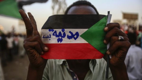 Sudanese protester holds the national flag with writings reading in Arabic "Civilian Only"  (AFP)