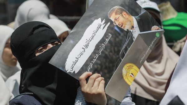 A woman wearing a niqab (full face veil) holds up a sign showing Egypt's late ousted president Mohamed Morsi, with captions in Arabic reading "our souls all long for Jerusalem, the martyr Mohamed Morsi" (AFP)
