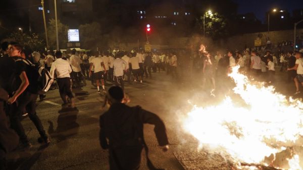 Ultra-orthodox Jews run as members of the Israeli Ethiopian community block the main entrance to Jerusalem  (AFP)