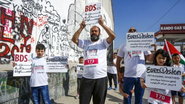 Activists hold banners calling for the boycott of Eurovision in the biblical town of Bethlehem in the occupied West Bank on 22 March 2019 [Musa AL ShaerAFP]