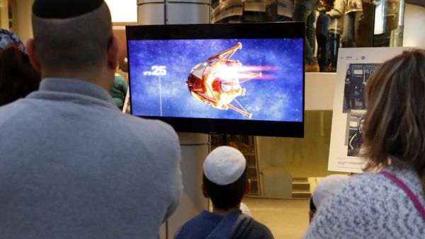 People watch a screen showing explanations of the landing of Israeli spacecraft, Beresheet's, at the Planetaya Planetarium in the Israeli city of Netanya, on April 11, 2019. (JACK GUEZ / AFP)