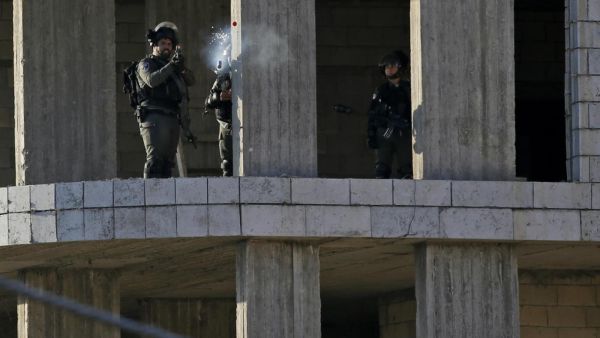 An Israeli soldier fires a tear gas canister at Palestinian stone throwers following a raid in the West Bank city of Ramallah. (AFP)