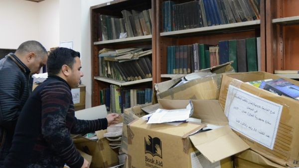 Iraqi men sort out books at the new library of Mosul University in Iraq's northern city of Mosul on April 17, 2019. (AFP)