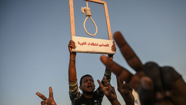 A Sudanese protester holds a hanging rope as others flash victory sign during a protest outside the army headquarters in the capital Khartoum on April 21, 2019. (AFP/ File)