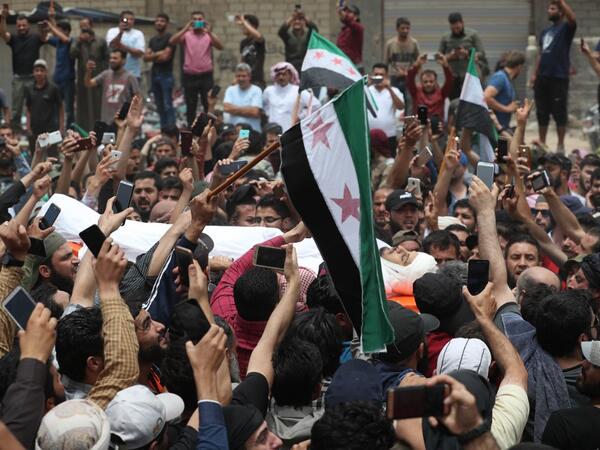 A picture taken on June 9, 2019 shows Syrians waving rebel flags during the funeral of late rebel fighter Abdel-Basset al-Sarout in al-Dana in Syria's jihadist-controlled Idlib region, near the border with Turkey. OMAR HAJ KADOUR / AFP