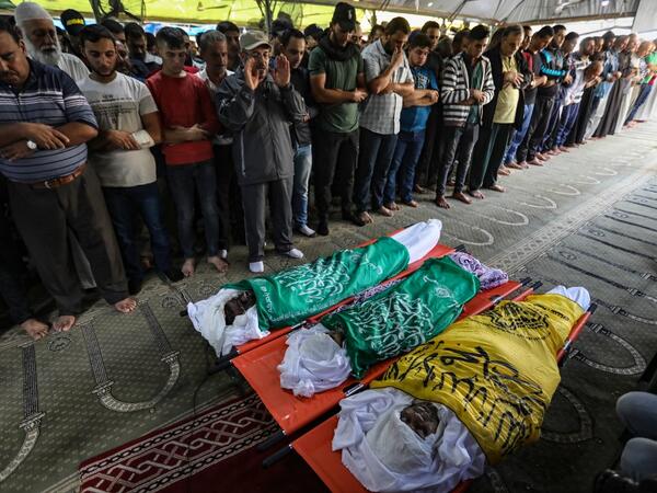 Palestinian mourners pray over the bodies of Rafat Ayad and his two sons Amir and Islam on during a funeral in Gaza City on November 13, 2019. Exchanges of fire triggered by Israel's targeted killing of a top militant in Gaza raged for a second day and showed little sign of easing, with 22 Palestinians killed. Fresh rocket barrages were fired at Israel, which responded with strikes on what it said were Islamic Jihad militant sites and rocket-launching squads in the Gaza Strip.  MAHMUD HAMS / AFP