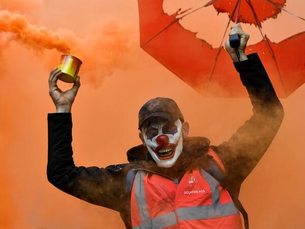 A man wearing the DC comic Joker character's mask and waving a smoke bomb takes part in a demonstration to protest against the pension overhauls, in Marseille, southern France, on December 5, 2019 as part of a national general strike. CLEMENT MAHOUDEAU / AFP