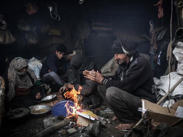 Members of a Palestinian family warm themselves by a fire during a cold weather spell in an empoverished neighbourhood on the outskirts in Gaza City on January 9, 2020. MAHMUD HAMS / AFP