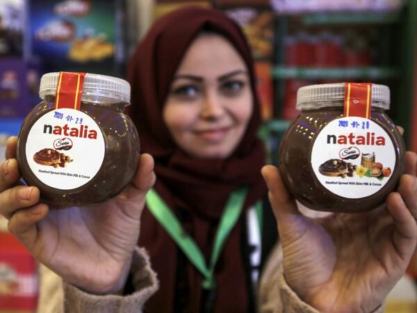 A shop employee holds up jars of a Gazan version of a world famous spread, dubbed 'Natalia', in Gaza city on February 12, 2020. Al-Arees's products are Gazan but their components are not, as few of the basic raw ingredients are produced in the impoverished Mediterranean coastal strip. MOHAMMED ABED / AFP