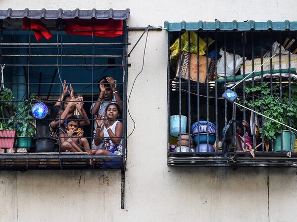 Residents watch from their flats' windows a music band formed by Sri Lankan Navy personnel as they play outside a housing complex during a government-imposed nationwide lockdown as a preventive measure against the COVID-19 coronavirus, in Colombo on April 9, 2020. ISHARA S. KODIKARA / AFP
