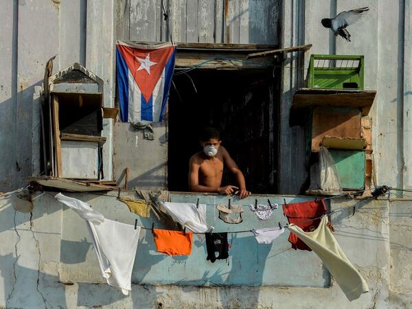 A man wears a face mask stands on his balcony in Havana, on April 11, 2020. Cuba hit out at the United States on Friday over its nearly 60-year-old embargo against the island nation, which Havana described as "even more cruel" given the suffering caused by the new coronavirus pandemic. The communist-run single-party island is finding it tough to source medical supplies and has already recorded 620 coronavirus cases and 16 deaths.