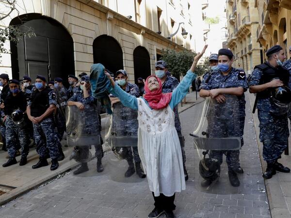 An elderly woman raises her arms in front of Lebanese security forces standing guard in front of the World Bank offices in the downtown district of the Lebanese capital Beirut on July 25, 2020, as demonstrators rally against the Bisri dam project, partly financed by the World Bank. The government says the Bisri dam is vital to tackling chronic water shortages. But activists say it will ravage most of the region's farmland and historic sites, and they also fear the consequences of building it on a seismic fa