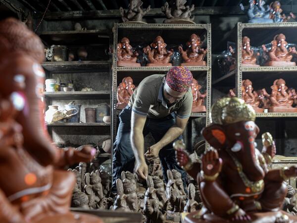 In this picture taken on August 11, 2020, Muslim potter Yusuf Zakaria Galwani inspects a clay idol of elephant headed Hindu god Ganesha at his workshop at Kumbharwada inside the Dharavi slums in Mumbai. After the coronavirus pandemic clobbered his pottery business, a Muslim artisan from India's largest slum turned to a Hindu god to revive his fortunes by making environmentally-friendly Ganesha idols for an upcoming festival. In Mumbai's Dharavi slum, Galwani worked alongside his two brothers to create 13-in