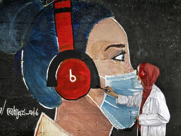 A Palestinian student paints a mural of a mask-clad girl in Gaza City on October 22, 2020, amid the novel coronavirus pandemic crises. Mohammed ABED / AFP