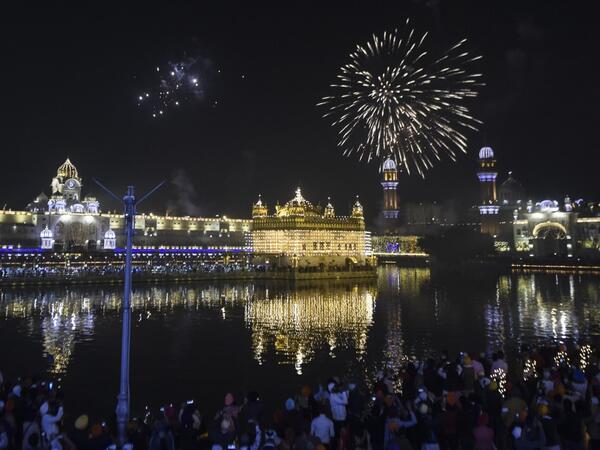 Sikh devotees watch as fireworks explode on the occasion of Bandi Chhor Divas, a Sikh festival coinciding with Diwali, the Hindu festival of light, over the Golden Temple in Amritsar on November 14, 2020. NARINDER NANU / AFP