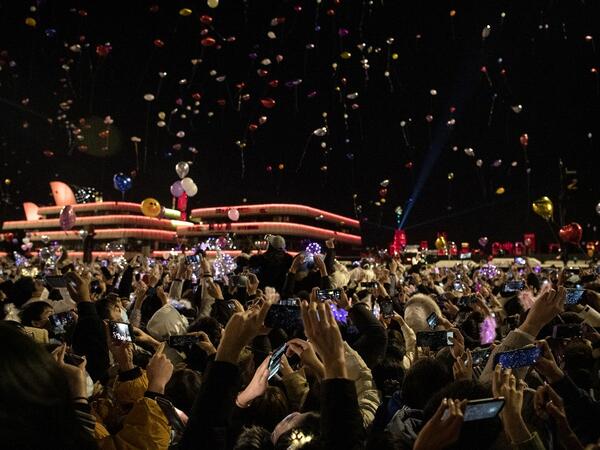 People wearing face masks release balloons during a New Year's countdown in Wuhan in China’s central Hubei province on January 1, 2021. NOEL CELIS / AFP