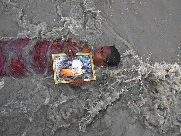 A Hindu pilgrim holds a picture of herself with late husband as she takes a holy dip at the confluence of Ganges and the Bay of Bengal during the Gangasagar Mela on the occasion of Makar Sankranti, a day considered to be of great religious significance in Hindu mythology, at Sagar Island, around 150 kms south of Kolkata on January 14, 2021. Dibyangshu SARKAR / AFP