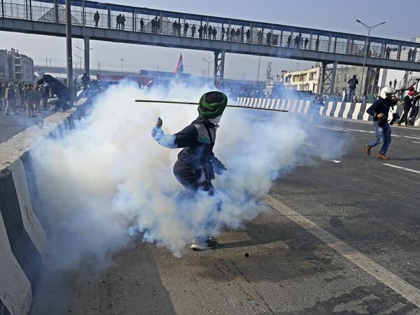 A farmer throws back a tear gas shell towards police during a tractor rally as farmers continue to protest against the central government's recent agricultural reforms in New Delhi on January 26, 2021. Sajjad HUSSAIN / AFP
