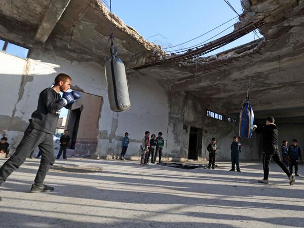 Syrian youths take part in a boxing workout held by local boxer Ahmad Dwara (unseen) inside a damaged building in the town of Atareb in the rebel-held western countryside of Syria's Aleppo province, on February 11, 2021. AAREF WATAD / AFP