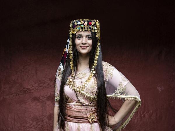 A Syrian Kurdish woman in traditional attire poses 