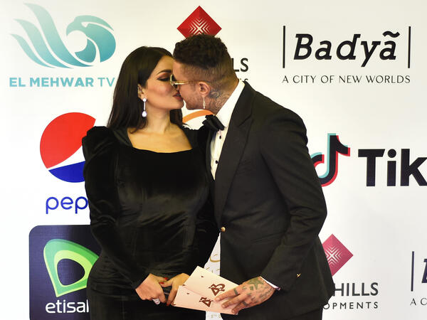 Egyptian actor Ahmed el-Fishawi kisses his wife Nada Kamel on the red carpet during the opening of the 43rd edition of the Cairo International Film Festival (CIFF) at the Cairo Opera House in the Egyptian capital on November 26, 2021. (Photo by Sayed HASAN / AFP)