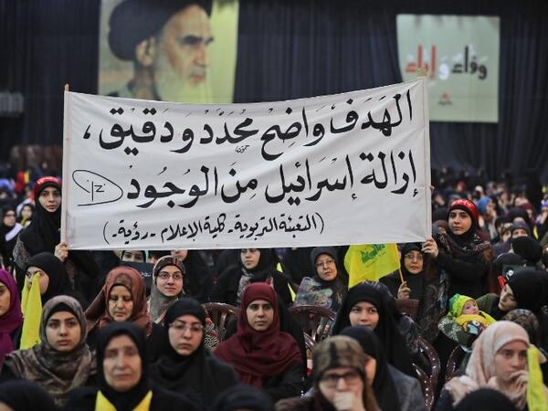 Supporters of Lebanese Hezbollah Leader gather as he delivers a televised speech during a ceremony held by the Shiite party in the capital Beirut, commemorating the party's killed leaders, on Feb. 16, 2018. The writing in Arabic reads: "The goal is clear, specific and precise...the removal of Israel from existence." 
(JOSEPH EID / AFP)